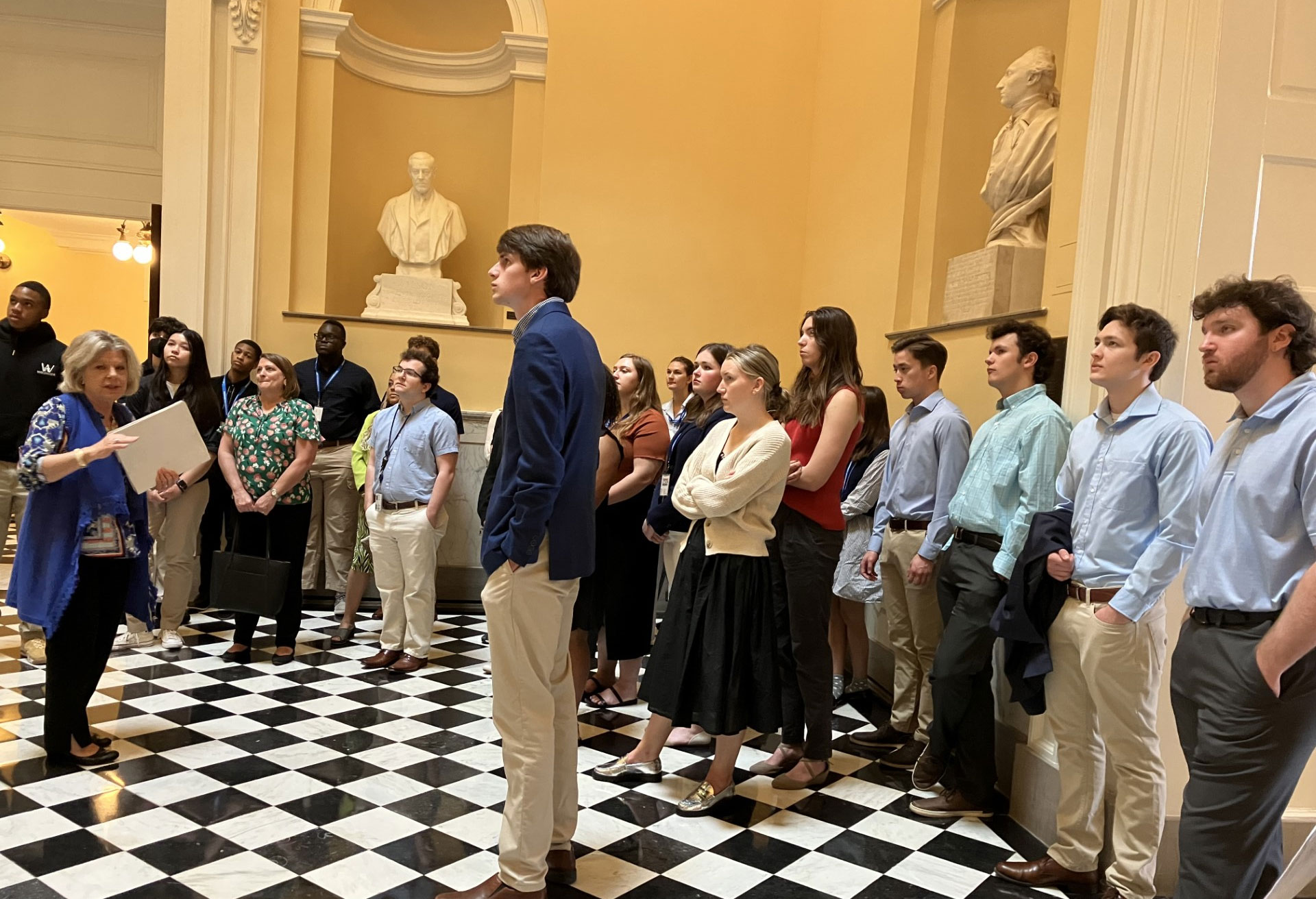 لوگوں کا ایک گروہ ایک مجسمے کے سامنے کھڑا ہے۔